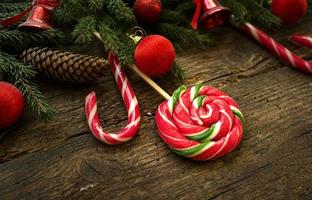 Weihnachtsgrenze mit Tannenzweigen, Zapfen, Weihnachtsschmuck und Zuckerstange auf rustikalen Holzbrettern foto