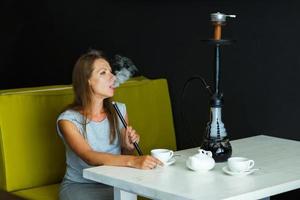 schön Frau Rauchen ein Huka und Trinken Tee im ein Cafe foto