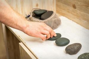 Masseur nimmt schwarz Massage Steine foto