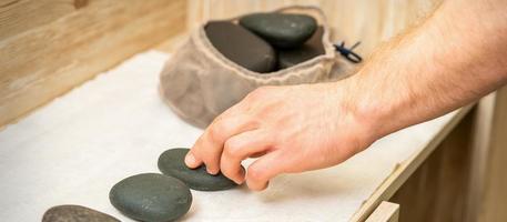 Masseur nimmt schwarz Massage Steine foto