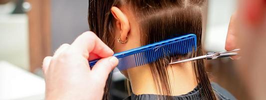 Friseur schneidet aus lange Haar von Frau foto