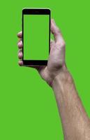 männlich Hand halten schwarz Handy mit Grün croma Bildschirm beim isoliert Grün Hintergrund. foto