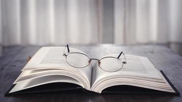 öffnen Buch Über hölzern Tabelle mit Brille auf Es. Bibliothek. Literatur. lesen. Studie