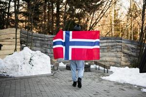 zurück von Mann halten Norwegen Flagge. skandinavisch Kultur, norwegisch Personen. foto