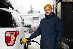 mann, der sein amerikanisches suv-auto an der tankstelle bei kaltem wetter betankt. foto