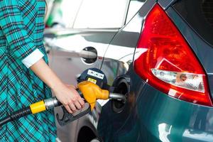 Frau füllt Benzin in das Auto beim ein Gas Bahnhof foto