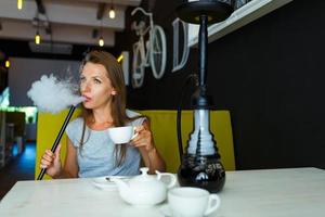 schön Frau Rauchen ein Huka und Trinken Tee im ein Cafe foto