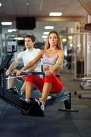 sportlich Mann und Frau Ausbildung auf Reihe Maschine im Fitnessstudio foto