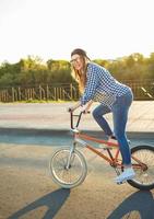 schön jung Frau im ein Hut Reiten ein Fahrrad im das Sonnenlicht draussen foto