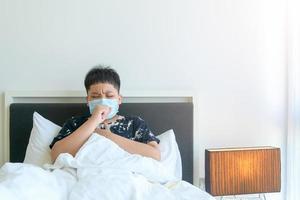 Kind krank mit covid-19 Husten und Truhe Schmerzen und nehmen Pflege von du selber beim heim, Zuhause Isolierung foto