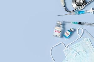 covid 19 Impfstoff mit Spritze und Stethoskop auf ein chirurgisch Maske auf Blau Hintergrund foto