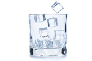 fallen Eis Würfel im zu leeren Felsen Glas oder alt gestaltet Glas isoliert auf Weiß foto
