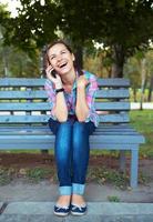 ein Porträt von ein lächelnd Frau im ein Park auf ein Bank reden auf das Telefon foto
