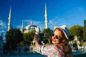 Mädchen im das Hut Herstellung Foto durch das Smartphone in der Nähe von das Blau Moschee, Istanbul