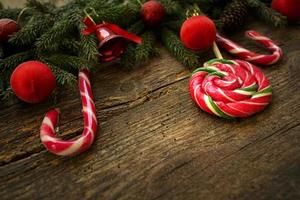 Weihnachtsgrenze mit Tannenzweigen, Zapfen, Weihnachtsschmuck und Zuckerstange auf rustikalen Holzbrettern foto