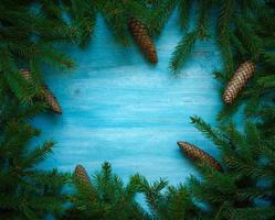 Weihnachten Baum Geäst mit Zapfen auf Blau hölzern Textur bereit zum Ihre Design foto