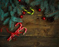Weihnachten Rand mit Tanne Baum, Zapfen, Weihnachten Dekorationen und Süßigkeiten Stock auf hölzern Bretter foto