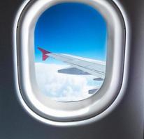 Flugzeugfenster, das über den Wolken fliegt foto