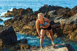 Athlet Frau Stehen nach Sport ausüben auf das Felsen durch das Meer foto
