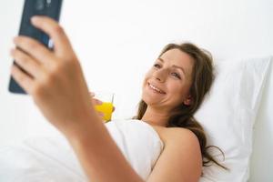 Frau mit Telefon auf das Bett foto
