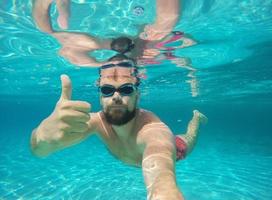 jung Bart Mann mit Brille Tauchen im ein Blau sauber Wasser foto