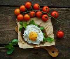 durcheinander Eier auf getoastet Brot mit Basilikum, Gewürze und Kirsche Tomaten foto