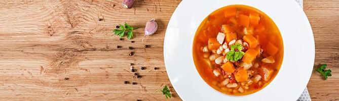 Tomate Hähnchen Suppe mit Kürbis und Weiß Bohnen im Weiß Schüssel. Banner. oben Aussicht foto