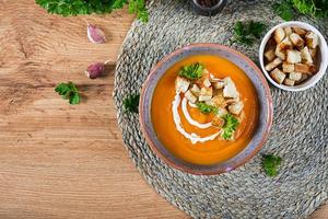 Kürbis Suppe im ein Schüssel serviert mit Petersilie und Croutons. vegan Suppe. das Erntedankfest Tag Lebensmittel. Halloween Mahlzeit. oben Aussicht foto