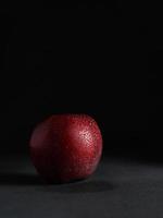schließen oben von rot saftig Apfel mit Tropfen von Wasser auf ein schwarz Hintergrund. isolieren. Kopieren Raum foto
