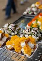 schließen hoch, knusprig thailändisch Nachspeisen gefüllt mit Creme, bestreut mit Gelb Kokosnuss Schalen. foto