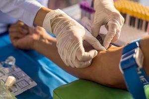 Nahansicht Sicht, ein Krankenschwester tragen Weiß Latex Handschuhe ist mit ein Spritze zu Reifenpanne ein Haupt Arterie. foto