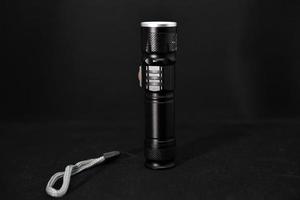 Metall schwarz Taschenlampe auf ein schwarz Hintergrund. Tasche Taschenlampe. foto
