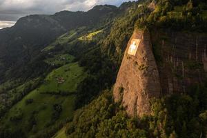 ein enorm schweizerisch Flagge ist Fest auf ein Cliff foto