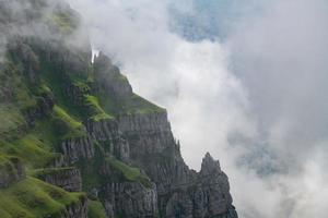 ein steil Cliff bewachsen mit Gras und versteckt durch Wolken foto