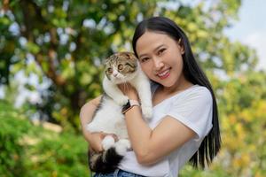 asiatisch Frau halten ein süß schottisch Katze im das Garten Haus Haustiere Konzept mit Kopieren Raum. foto