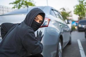 ein Dieb mit ein Raub Maske versuchen zu stehlen ein Automobil foto