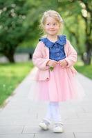 ein wenig Mädchen 3 Jahre alt Spaziergänge im das Park im ein Kleid und ein Rosa Pullover. foto