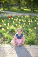 ein wenig Mädchen 3 Jahre alt Spaziergänge im das Park im ein Kleid und ein Rosa Pullover. foto