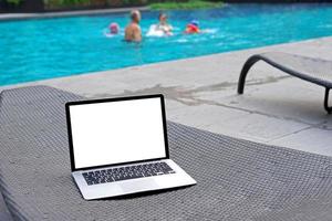 Laptop mit leer Bildschirm zum kreativ Design auf Sonnenbank in der Nähe Schwimmen Schwimmbad Hintergrund. Computer Notizbuch mit Monitor Ausschnitt Pfad zum Geschenk Landung Seite Design. Laptop Computer spotten oben Vorlage foto