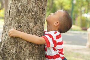 Konzept von Speichern das Welt Junge umarmen ein Baum foto