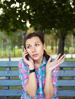 Porträt von ein jung Frau im ein Park reden auf das Telefon foto