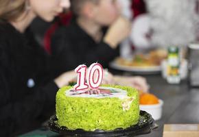 festlich Kuchen mit das Nummer zehn auf das Hintergrund von verschwommen Gäste. foto