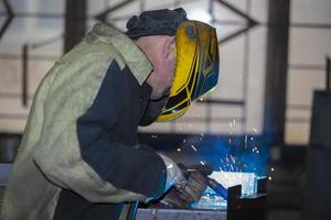 ein Schweißer funktioniert mit Metall im ein Fabrik Geschäft. foto