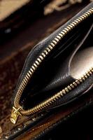 Leder Brieftasche mit ein golden Reißverschluss Nahansicht auf ein dunkel Hintergrund. foto