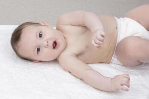 ein sechs Monate alt Baby Junge im ein Windel Lügen auf ein Windel. das Konzept von Mutterschaft und Vaterschaft. foto