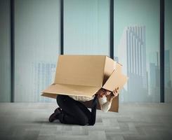 Angst Geschäftsmann versteckt unter ein Box foto
