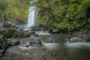 Wasser fallen auf tropisch Wald. Wasser fließend durch Fluss Stein. das Aufnahmen ist geeignet zu verwenden zum Natur Filmaufnahme, und Reise Ziel Filmaufnahme. foto