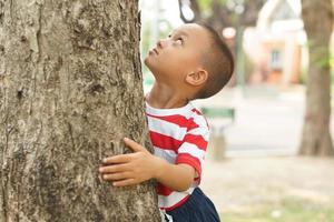 Konzept von Speichern das Welt Junge umarmen ein Baum foto