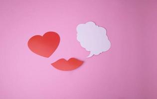 auf ein Rosa Hintergrund Papier rot Lippen und ein Herz und ein Weiß Wolke zum Wörter. foto