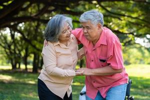 Ein asiatischer Senior fiel im Park auf den liegenden Boden, nachdem er gestolpert war und vor Schmerzen geweint hatte, und seine Frau kam, um zu helfen. konzept der alten versicherung und gesundheitsversorgung foto